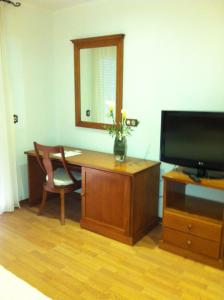 un escritorio con TV y un jarrón con flores. en Hotel Donde Caparrós, en Carboneras