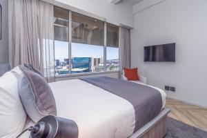 Un dormitorio con una cama grande y una ventana grande. en 1819 at one thibault apt, en Ciudad del Cabo
