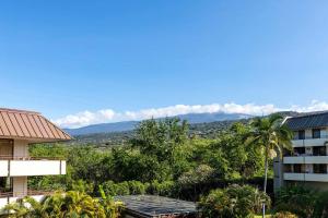 a view of a building with trees and a mountain at Beachside Condo with Ocean Views in Kailua-Kona