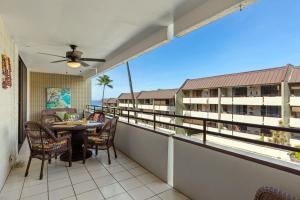 a balcony with a table and chairs and a view of a building at Beachside Condo with Ocean Views in Kailua-Kona