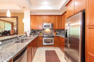 a kitchen with wooden cabinets and stainless steel appliances at Mauna Lani Fairways - Luxury Accommodations in Waikoloa