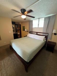 a bedroom with a bed with a ceiling fan at Kona Alii - Oceanview Pool Shops & Restaurants in Kailua-Kona