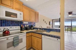 a kitchen with a sink and a stove top oven at Kona Alii - Oceanview Pool Shops & Restaurants in Kailua-Kona