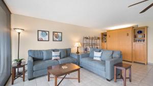 a living room with a blue couch and a table at Kona Alii - Oceanview Pool Shops & Restaurants in Kailua-Kona