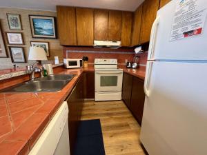 a kitchen with a white refrigerator and a sink at Oceanfront Vintage Retreat in Kailua-Kona in Kailua-Kona