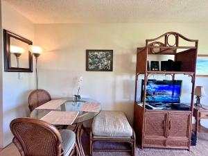 a dining room with a glass table and a tv at Kona Isle Oceanfront Condo in Kailua-Kona