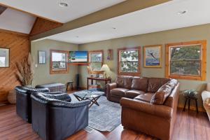 a living room with leather furniture and windows at 6090 - Seas The Day NH in Nags Head