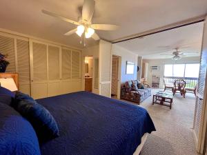 a bedroom with a blue bed and a ceiling fan at Kona Mansions - Ocean Views & Amenities in Kailua-Kona
