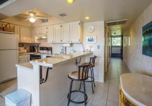 a kitchen with a counter and two stools in it at Casa De Emdeko Condo with Pool AC & Ocean Views in Kailua-Kona