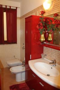 een badkamer met een wastafel, een toilet en een rode kast bij Villa Antares in Custonaci