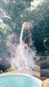 a boy jumping into a swimming pool with a water fountain at The Gambo Shepherd's Hut in Kidwelly