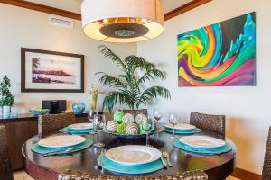 a dining room with a table with chairs and a painting at Beachfront Condo in Ko Olina Paradise in Kapolei
