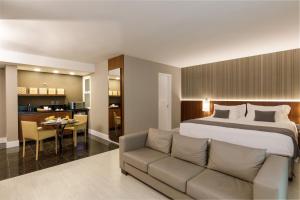 a bedroom with a bed and a couch and a table at Promenade Palladium Leblon in Rio de Janeiro