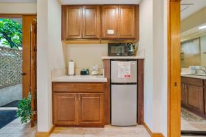 a small kitchen with wooden cabinets and a refrigerator at Romantic Studio in Waikoloa Beach Resort in Waikoloa