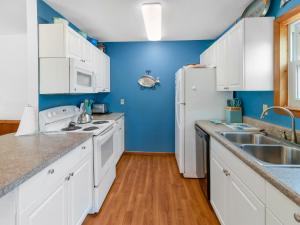 a kitchen with white cabinets and a blue wall at 2130 - Luna Blu Cottage in Sea Hawk
