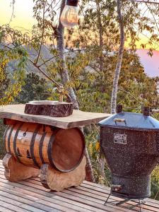 a table and a trash can sitting next to a barrel at Wagon Cella Faroeste Acima das Nuvens Spa Ofurô Aquec Campos do Jordão in Campos do Jordão