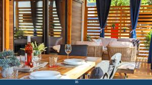 een houten tafel met borden en wijnglazen op een patio bij Mobile Homes Jaki in Biograd na Moru
