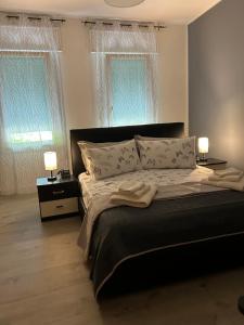 a bedroom with a large bed with two lamps and two windows at Larocca Tourist Home 5 Bassano in Bassano del Grappa