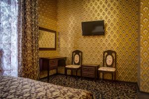 a bedroom with two chairs and a bed and a tv at Frant Hotel in Volgograd