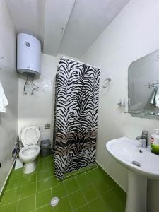La salle de bains est pourvue d'un rideau de douche à l'impression zébrée et d'un lavabo. dans l'établissement Minga Apartments, à Pogradec