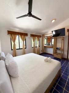 a bedroom with a white bed with a ceiling fan at Hotel Solana Bacalar Lakefront in Bacalar
