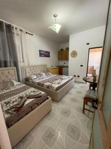 Un dormitorio con dos camas y una mesa y un escritorio. en Aura Rooms, en Durrës