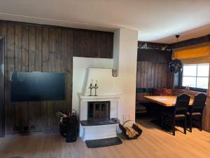 a living room with a fireplace and a dining room table at Norefjell Ski in - Ski out in Noresund