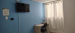 a room with a desk and a television on a blue wall at Guacamayas in Santa Marta
