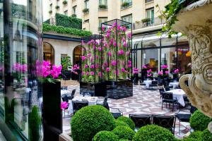 un patio con mesas, sillas y flores rosas en Four Seasons Hotel George V Paris, en París
