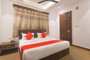 a bedroom with a large bed with red pillows at Hotel O Rudraksh in Indore