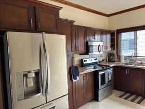 a kitchen with a white refrigerator and wooden cabinets at Casa Pors Luxury Apartment with Security, Pool, & Gym in Liguanea