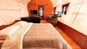 a bedroom with a bed and a tv in it at Wagon Cella Faroeste Acima das Nuvens Spa Ofurô Aquec Campos do Jordão in Campos do Jordão
