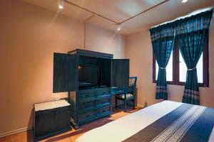 a bedroom with a bed and a tv and a dresser at Casa de los Frailes in Oaxaca City