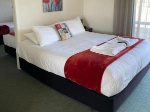 ウェストポートにあるBuller Bridge Motelの白いシーツと枕が付いた大きなベッドのある寝室