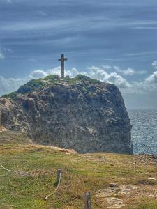 una cruz en la cima de una colina con el océano en Aguasoleil, en Saint-François