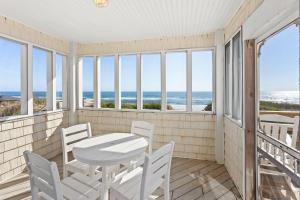 a balcony with a table and chairs and the ocean at 6175 - Longview Cottage in Whalebone