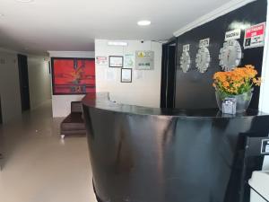 a lobby with a black counter with a vase of flowers at Hotel Santiago Plaza in Bogotá