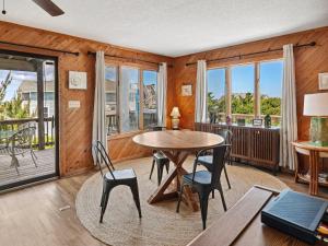 a dining room with a table and chairs and windows at 2030 - Horizon`s Summit in Duck