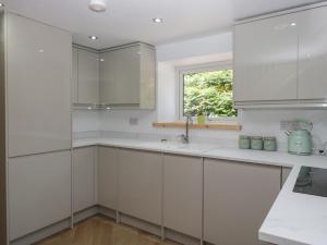 une cuisine blanche avec des armoires blanches et une fenêtre dans l'établissement Old Post Office Cottage, à Ulverston