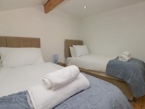 une chambre avec deux lits avec des serviettes dessus dans l'établissement Old Post Office Cottage, à Ulverston 31 autres photos