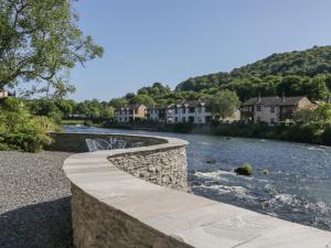 un pont de pierre sur une rivière avec des maisons dans l'établissement Old Post Office Cottage, à Ulverston