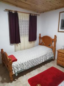 sypialnia z drewnianym łóżkiem i czerwonym dywanem w obiekcie Casa ecologica, autosuficiente en Lomo Blanco, dentro de una casa rodeada de naturaleza w mieście San Juan de la Rambla