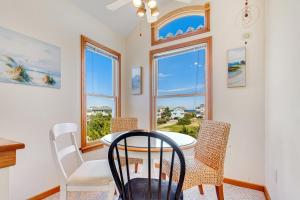 a dining room with a table and chairs and windows at 1700 - Carolina Delight in Poplar Branch +46 photos