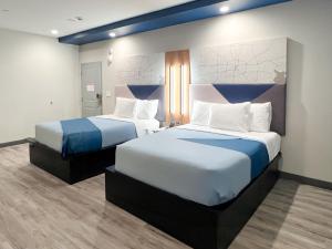 a hotel room with two beds with blue and white sheets at Crystal Inn - NorthWest - 290 in Houston