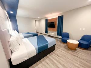 a bedroom with a bed and a tv and blue chairs at Crystal Inn - NorthWest - 290 in Houston