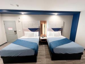 two beds in a room with blue and white at Crystal Inn - NorthWest - 290 in Houston