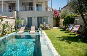 einen Hinterhof mit einem Pool mit Stühlen und einem Haus in der Unterkunft Noesta Alaçatı in Alacati