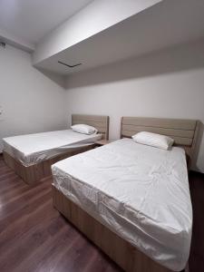two beds in a room with white walls and wood floors at Luxury apartment new giza Compound in Abū Rawwāsh +26 photos