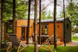 a cabin in the woods with two chairs and a house at Domek Księża Góra in Krasnobród