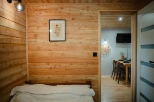 a bedroom with wooden walls and a bed in a room with a table at Domek Księża Góra in Krasnobród
